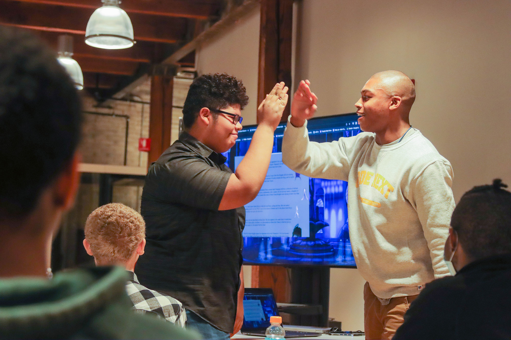 Two Code Next students high-five.