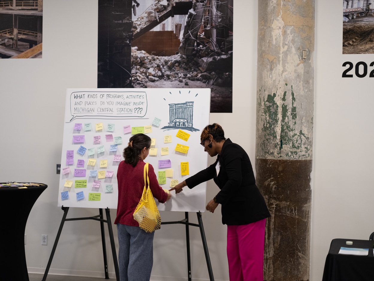 During a community event, two women work together to adds post-it note to a board containing ideas for programs, activities and places imagined for Michigan Central Station.During a community event, two women work together to adds post-it note to a board containing ideas for programs, activities and places imagined for Michigan Central Station.