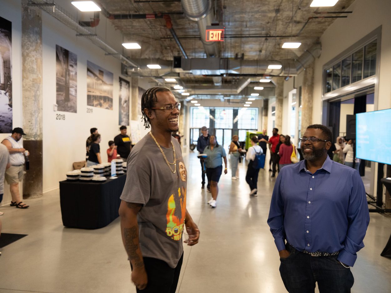Two men gathered at the Newlab at Michigan Central building share a laugh during a friendly conversation.